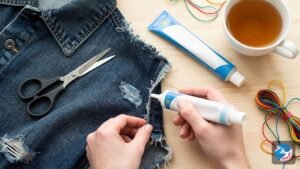 A flat lay of craft supplies on a wooden table, featuring a denim jacket with a neatly applied patch, showing a successful fabric glue repair.