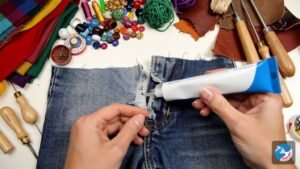 A variety of crafting supplies laid out on a surface, including colourful fabrics, beads, leather pieces, and small wood carving tools.